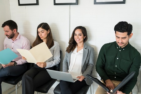 Confident candidate using laptop while sitting with competitors at job interview in office